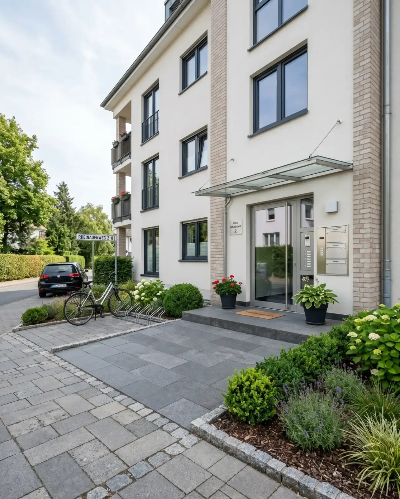 Gepflegter Eingangsbereich eines Mehrfamilienhauses mit aufgeräumten Wegen, Bepflanzung und Klingelanlage, typisch für unseren Hausmeisterservice in Bad Honnef.
