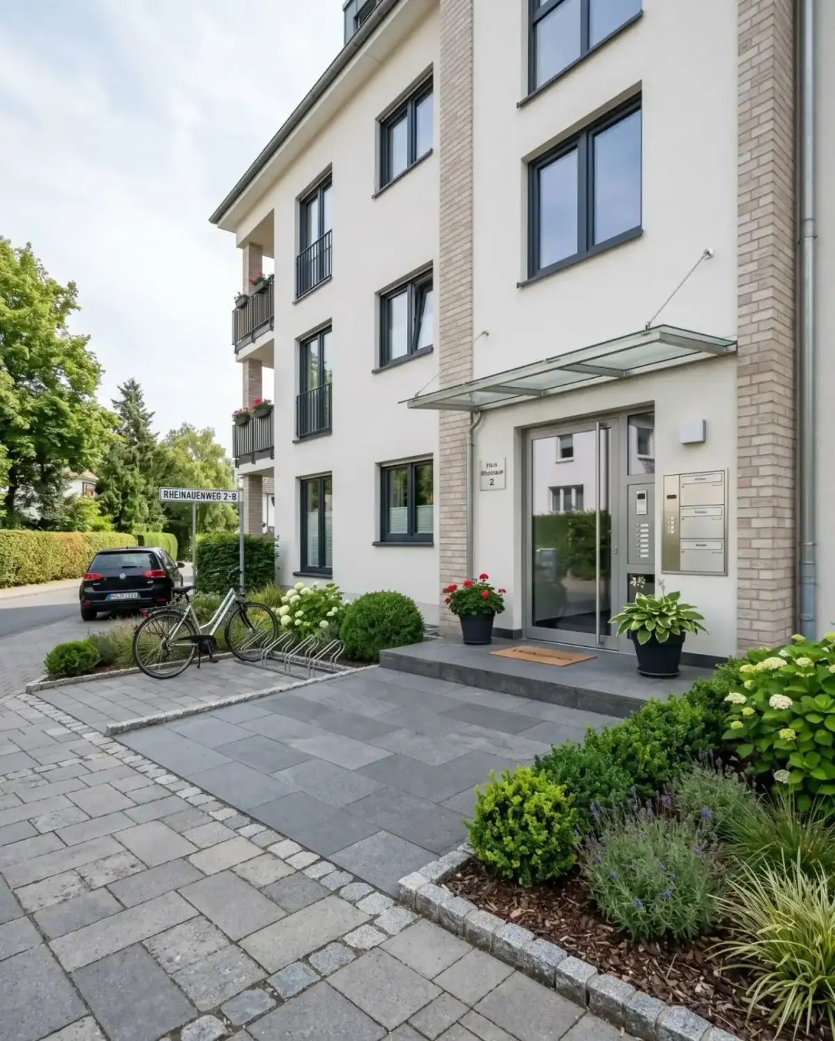 Gepflegter Eingangsbereich eines Mehrfamilienhauses mit aufgeräumten Wegen, Bepflanzung und Klingelanlage, typisch für unseren Hausmeisterservice in Köln, Bonn & Rhein-Sieg.