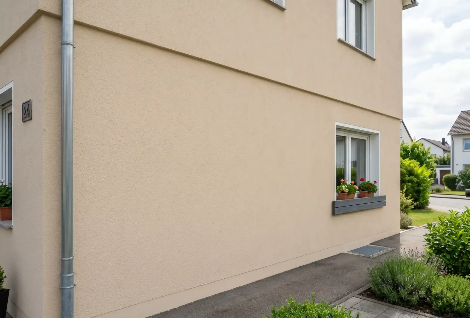 Beige verputzte Hausfassade nach erfolgreicher Graffiti-Entfernung im Tageslicht, Oberfläche gleichmäßig und unbeschädigt.