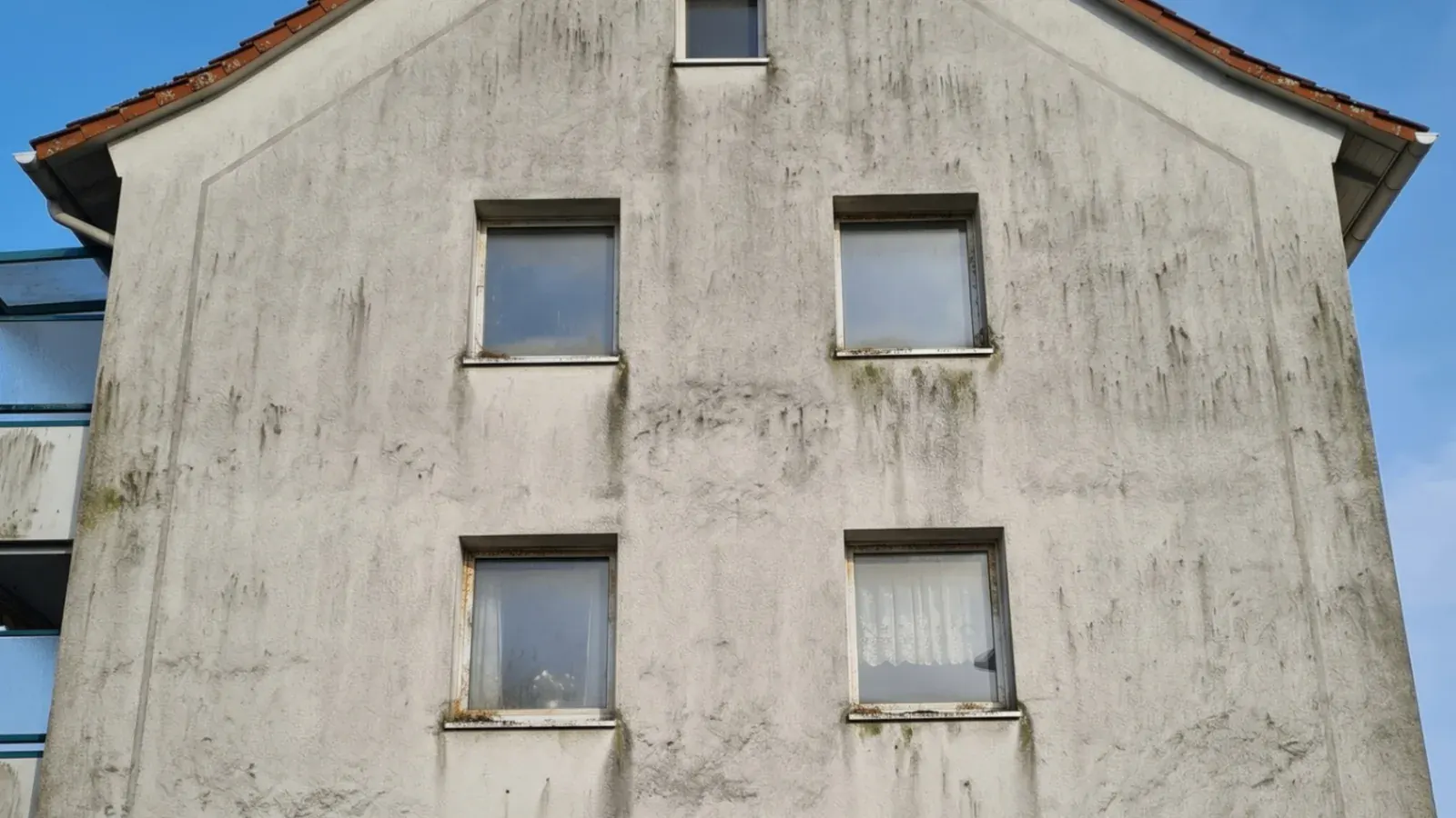 Mehrfamilienhaus mit stark verschmutzter Putzfassade vor der professionellen Reinigung in Hennef